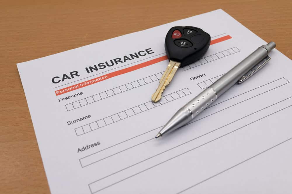 Auto insurance application with car key and pen