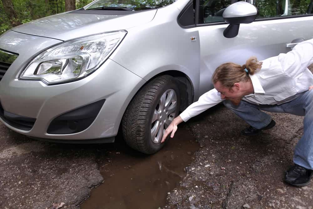 man checking the damage on his tires because he didn't avoid a pothoe