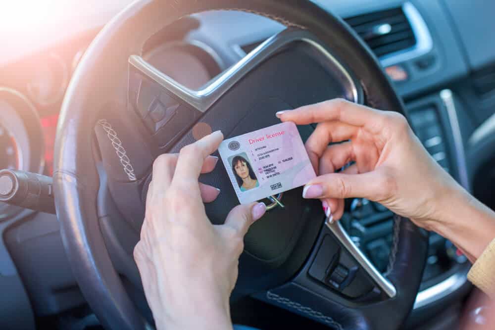 woman inside car holding her license after getting it back woth sr22 insurance