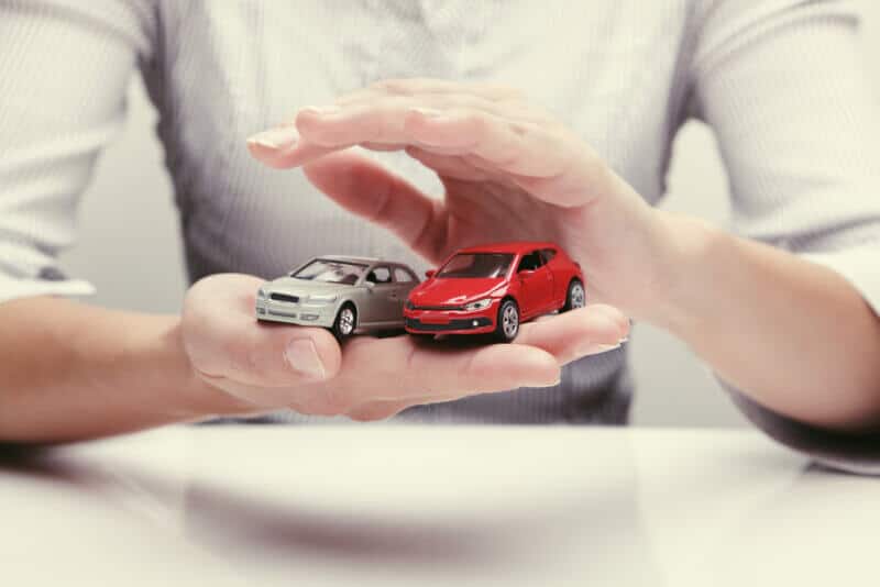 Family Car Insurance hands holding two toy cars to symbolize multiple car insurance
