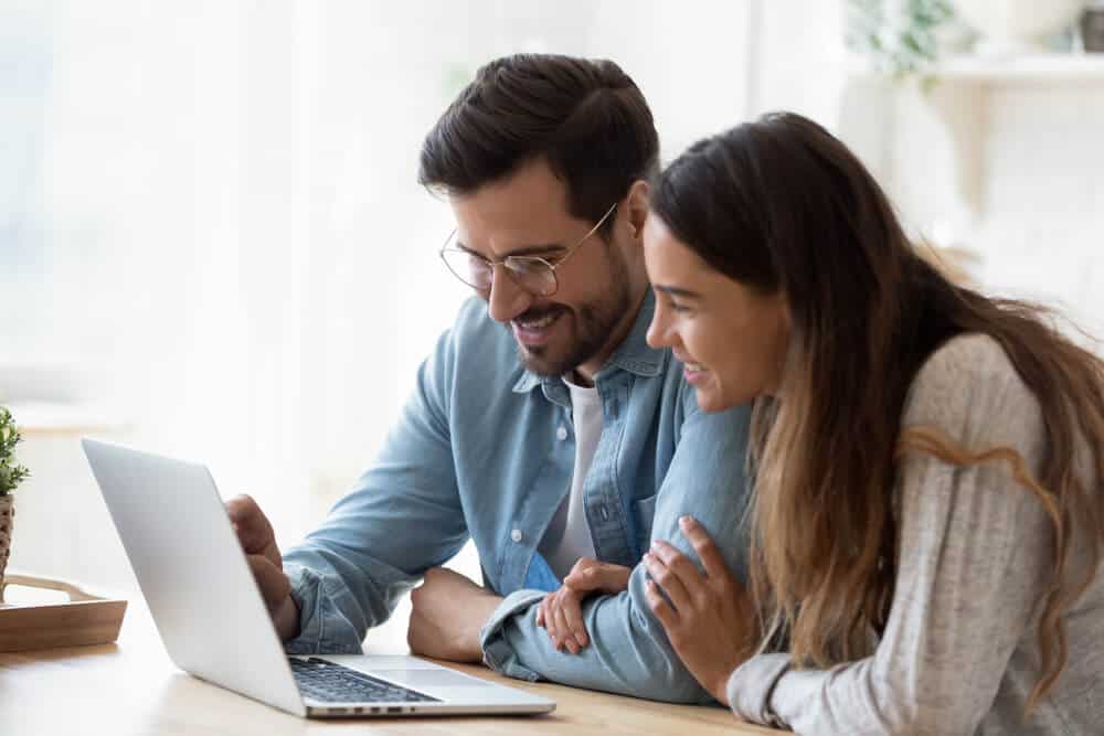happy couple with laptop finding cheap car insurance