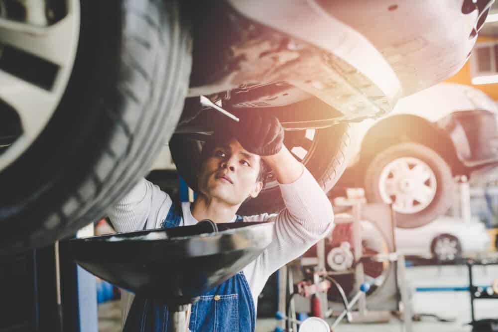 young mechanic changing a cars oil