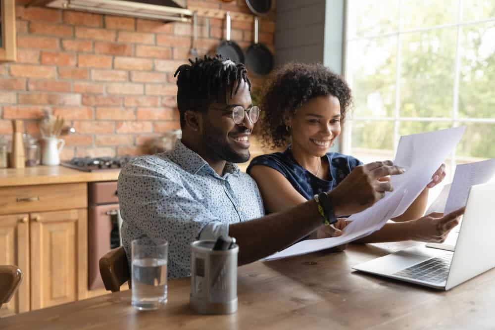 happy couple in desk with laptop looking at auto insurance policy