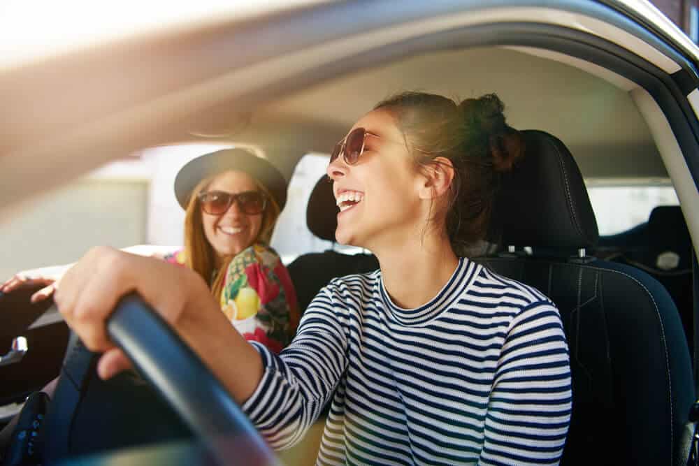 two happy women in car with an insurance policy