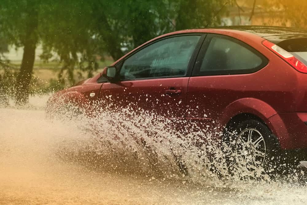 car in motion in rain big puddle of water spray from the wheels