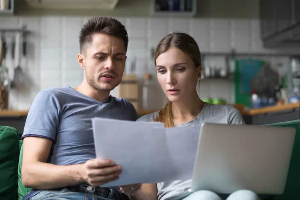 Serious couple checking bills with papers and laptop