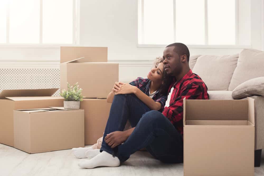 young african american couple surrounded by boxes moving into apartment