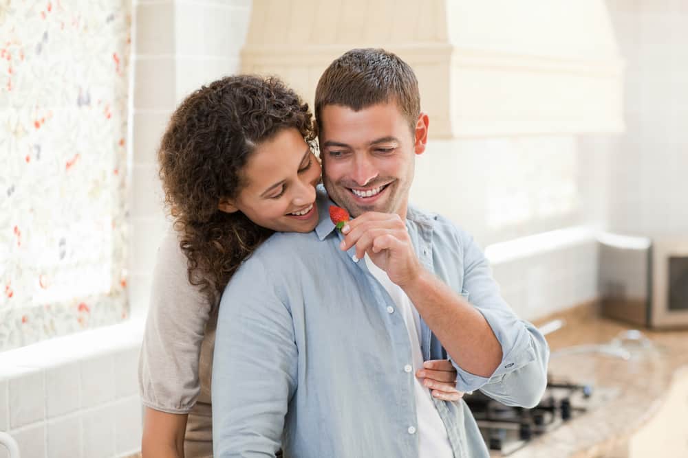 Young couple with man offering strawberry to woman