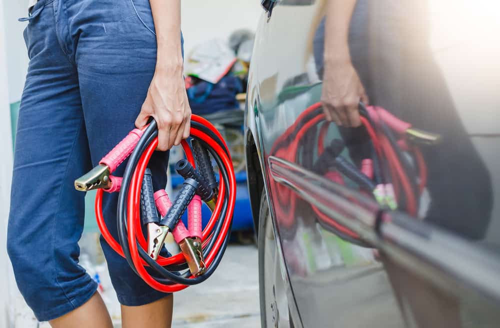 person walking to car with jumper cables