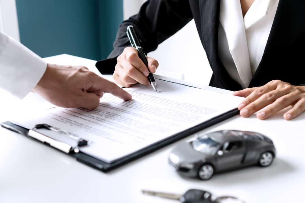 person filling out car insurance claim on clipboard