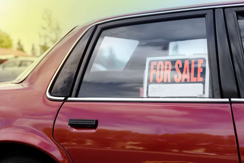 for sale sign in window of red car