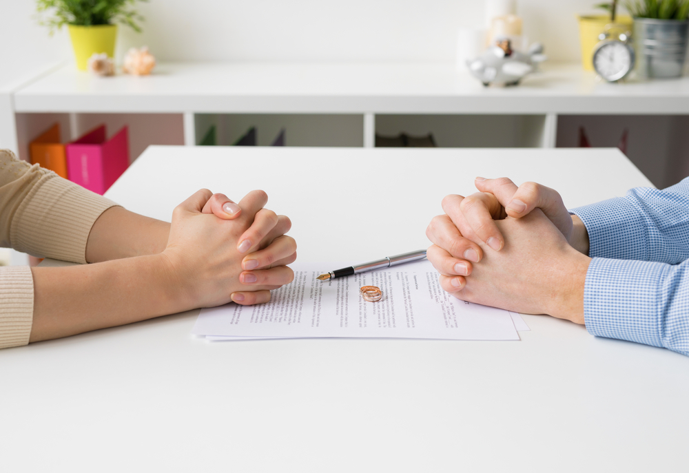 couple sitting down between divorce settlement paperwork