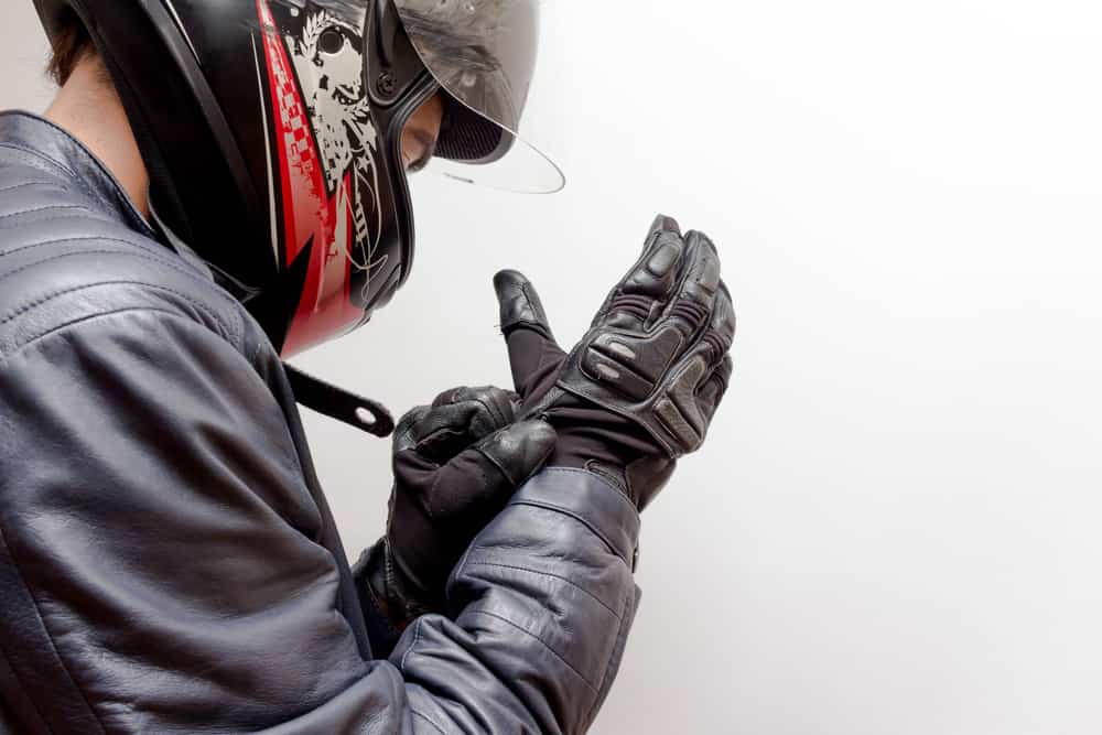 motorcyclist putting on gloves with helmet on