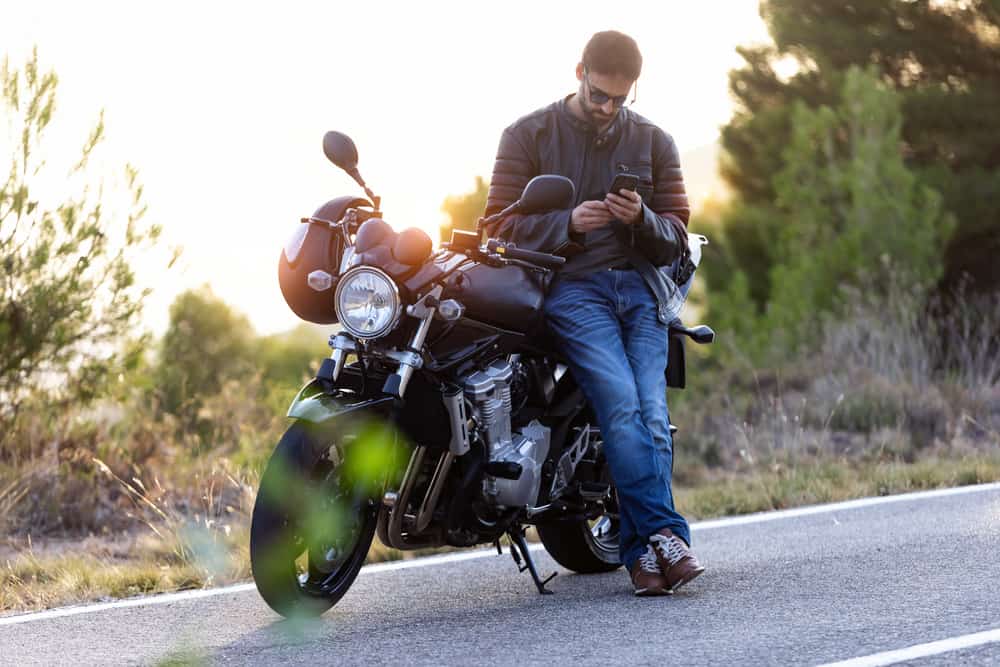 man leaning against motorcycle on phone