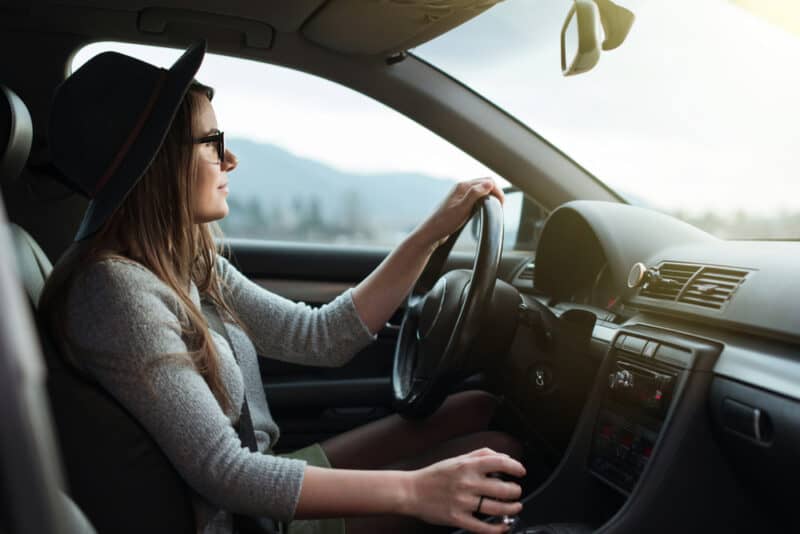 Young,Hipster,Woman,With,Eyeglasses,And,Hat,Driving,The,Car. woman driving safely in car