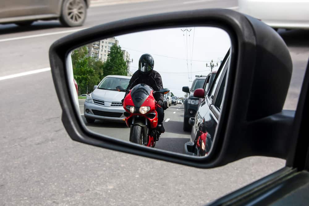 side mirror of car with view of motorcyclist