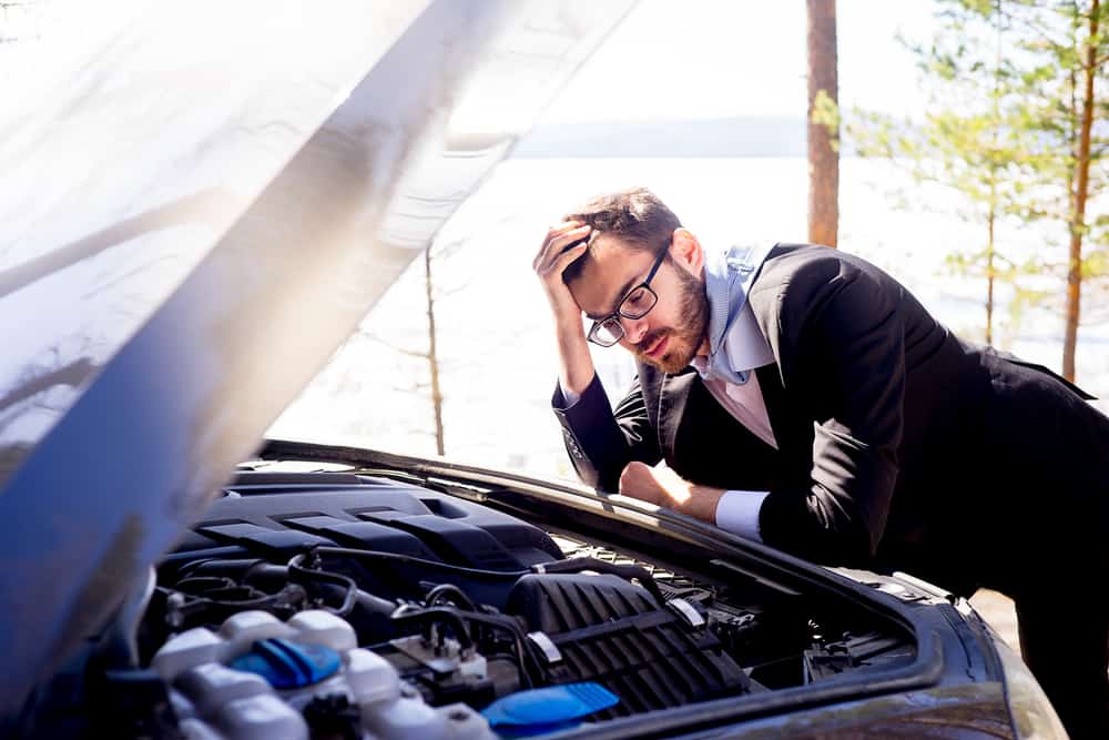 man looking under hood of car