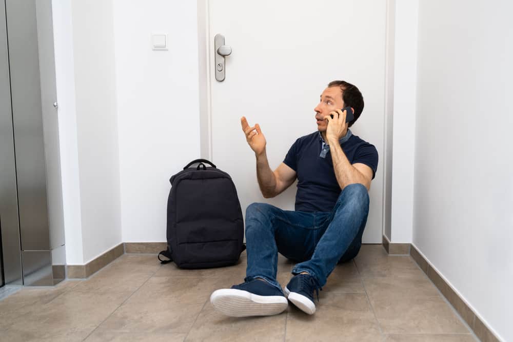 man sitting outside apartment door without keys