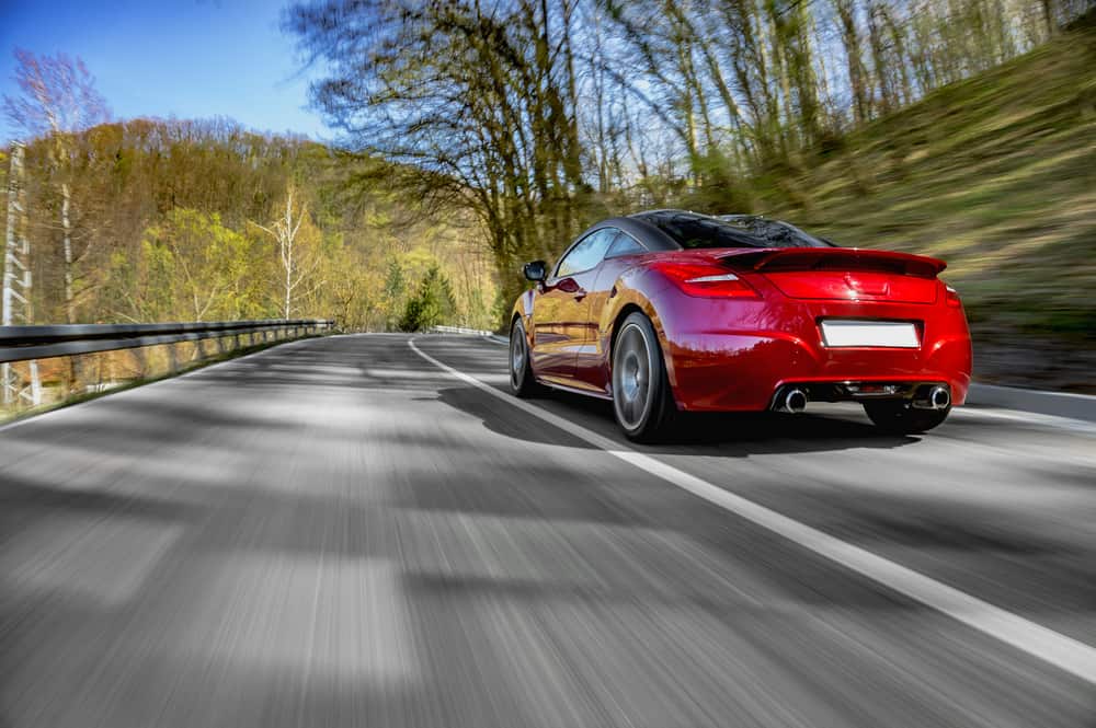 red sports car driving down road