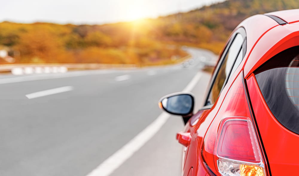 red car driving down highway