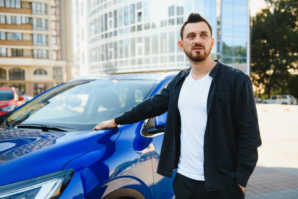 man standing next to blue car