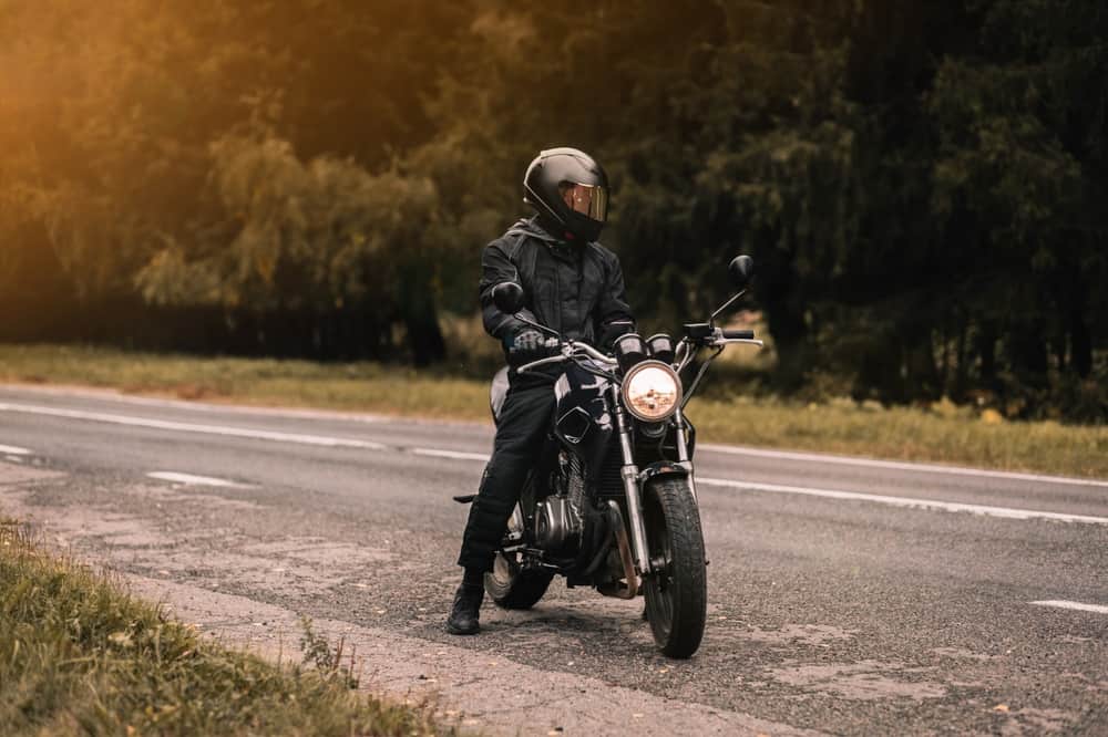 man on motorcycle stopped on side of country road