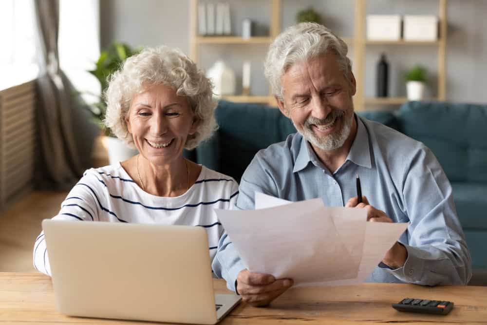 Older couple smiles as they do their taxes with life insurance