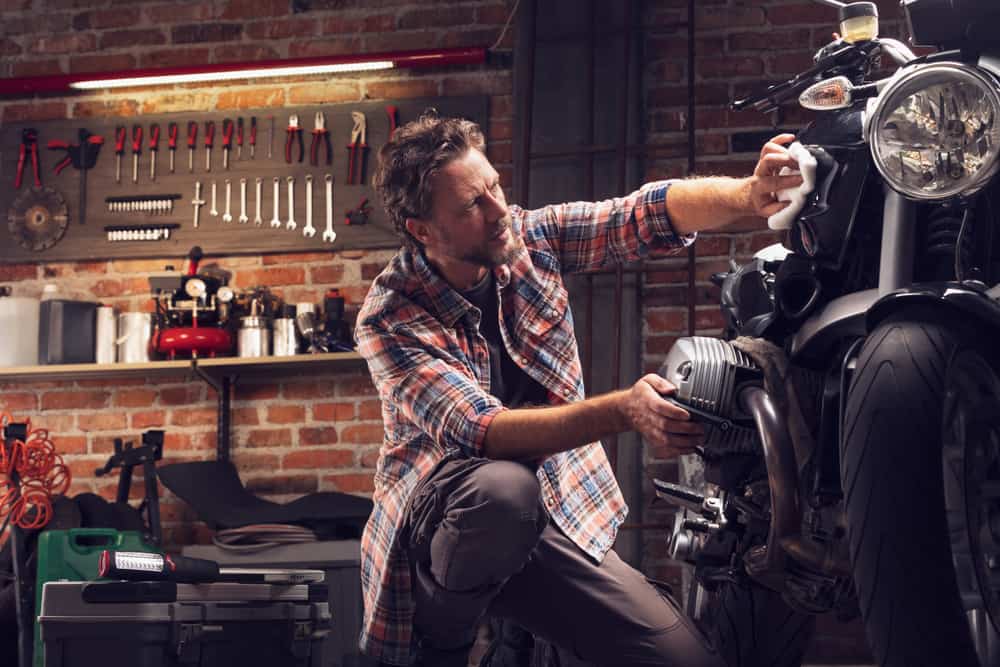 man works on his motorcycle in his garage