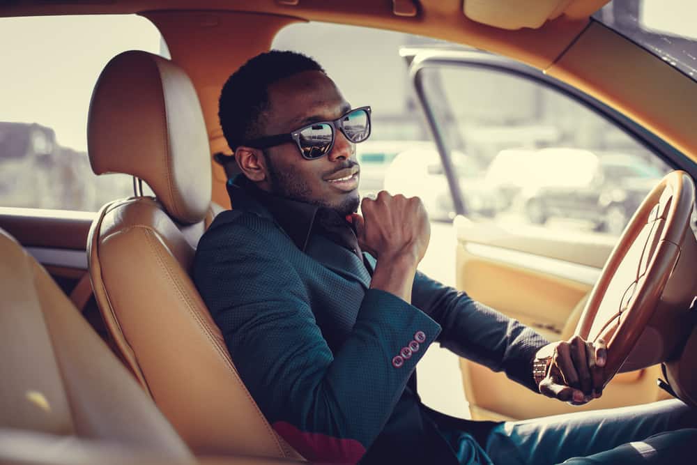 Handsome African-American man wearing sunglasses behind the wheel of a car