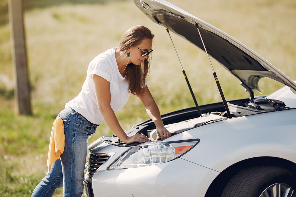 woman looking into the engine of her car